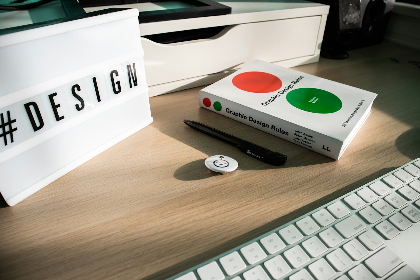 Strumenti di graphic design su una scrivania di legno, tra cui una lightbox e un libro.