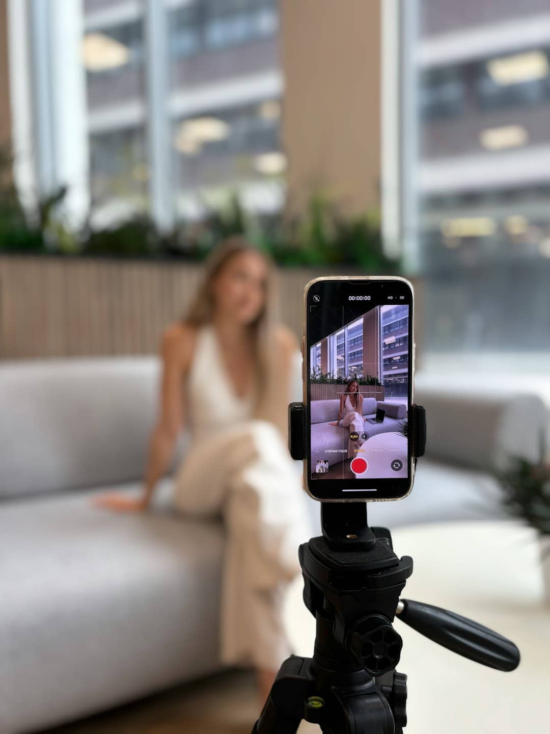 Una donna seduta sul divano mentre registra contenuti video.