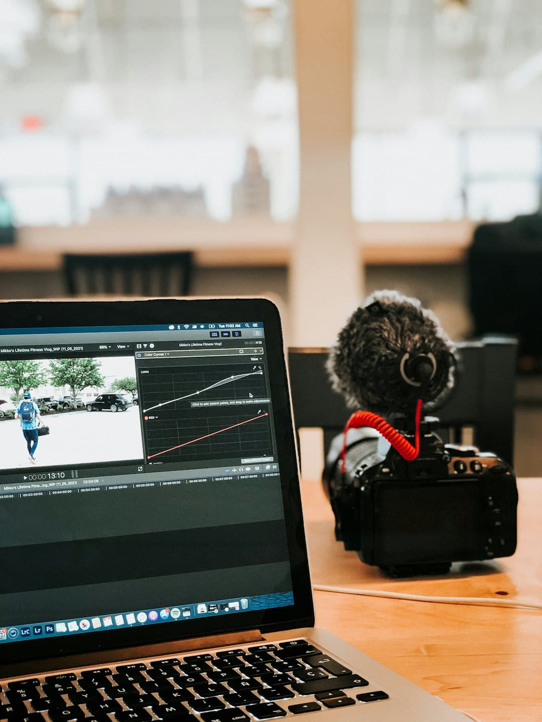 Persona che edita video su un laptop con attrezzatura fotografica.