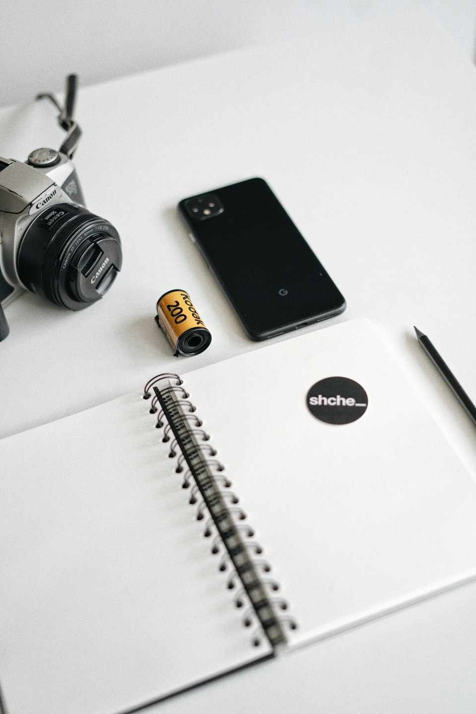 Macchina fotografica digitale e forniture creative per ufficio su una scrivania bianca.